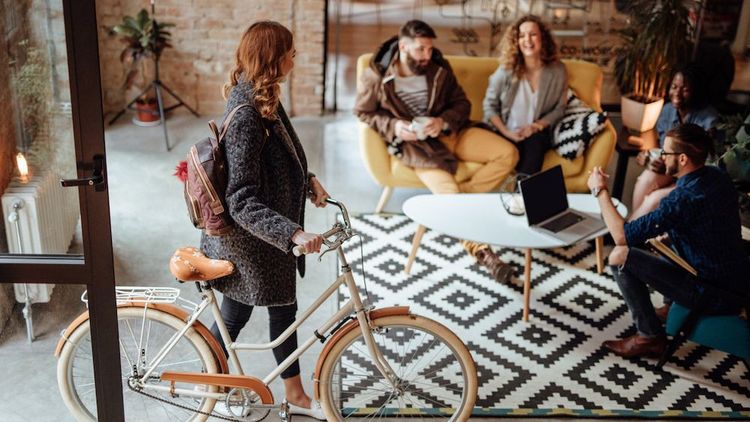 Junge Frau mit Fahrrad geht ins Büro