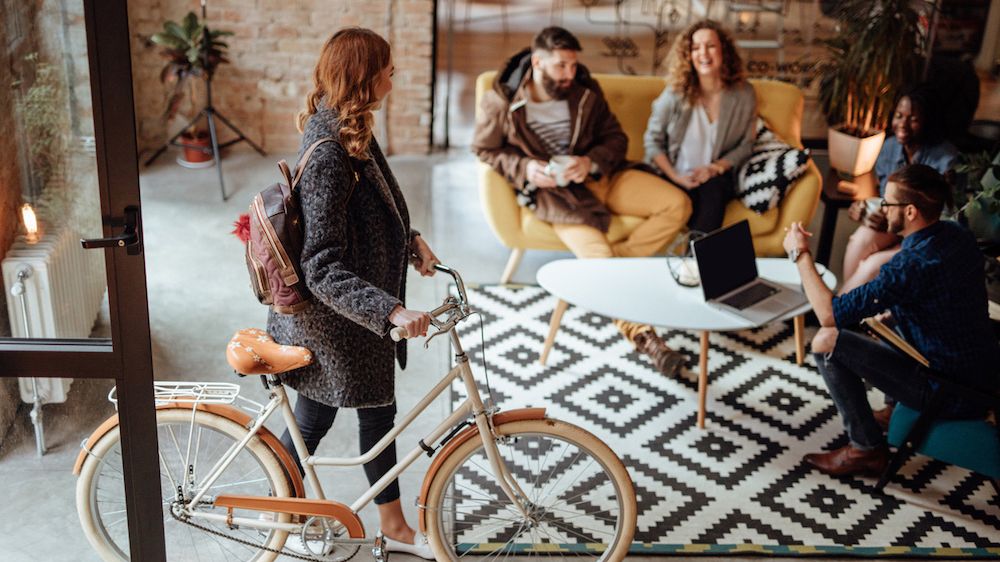 Junge Frau mit Fahrrad geht ins Büro